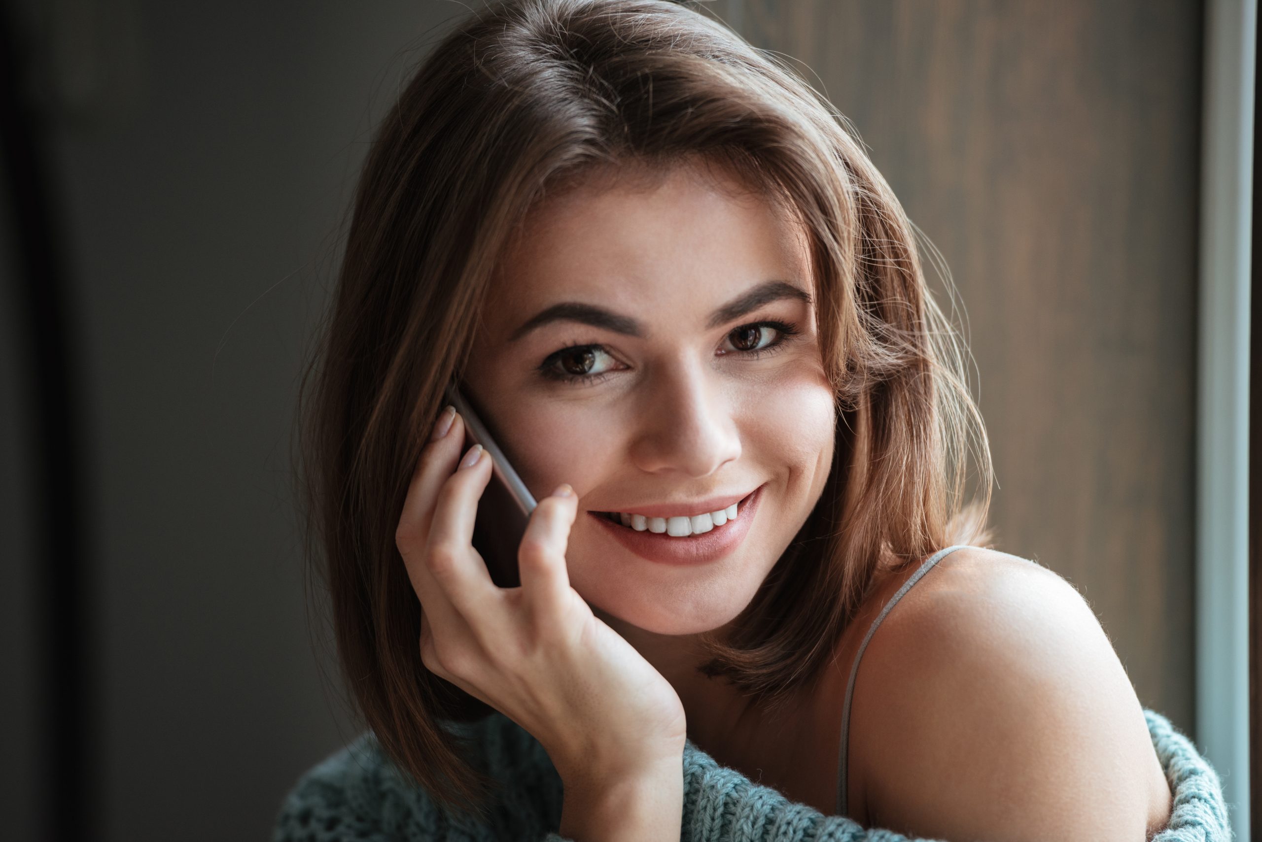 smiling woman chatting on phone in cafe near window SBI 302845906 scaled